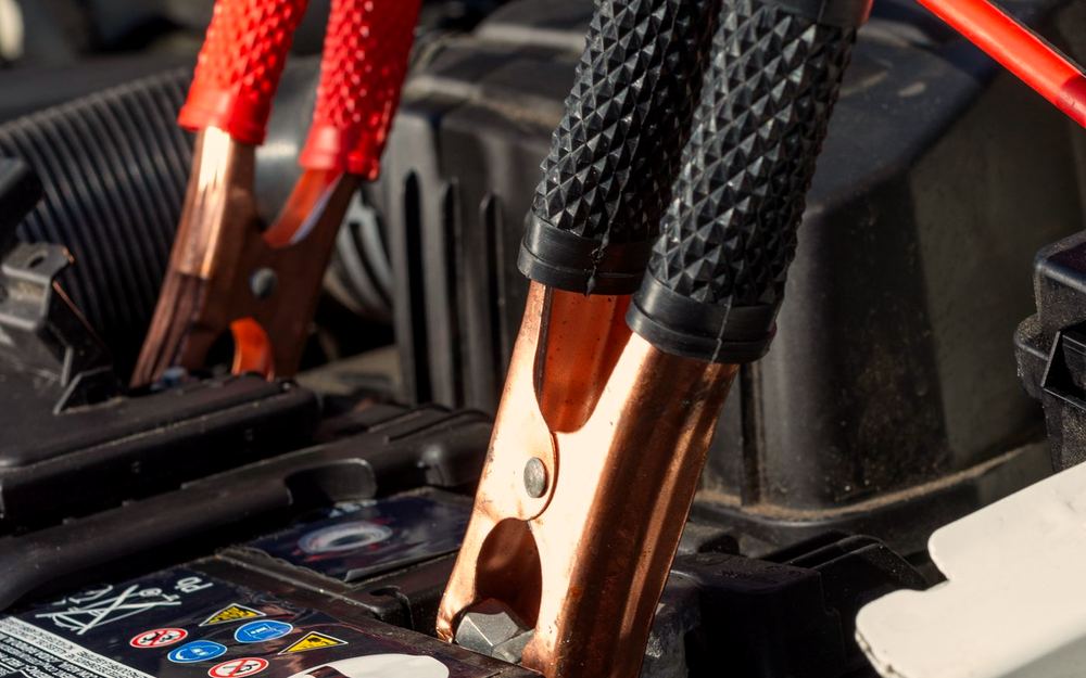 Jumper leads clamped to a car battery in the engine bay