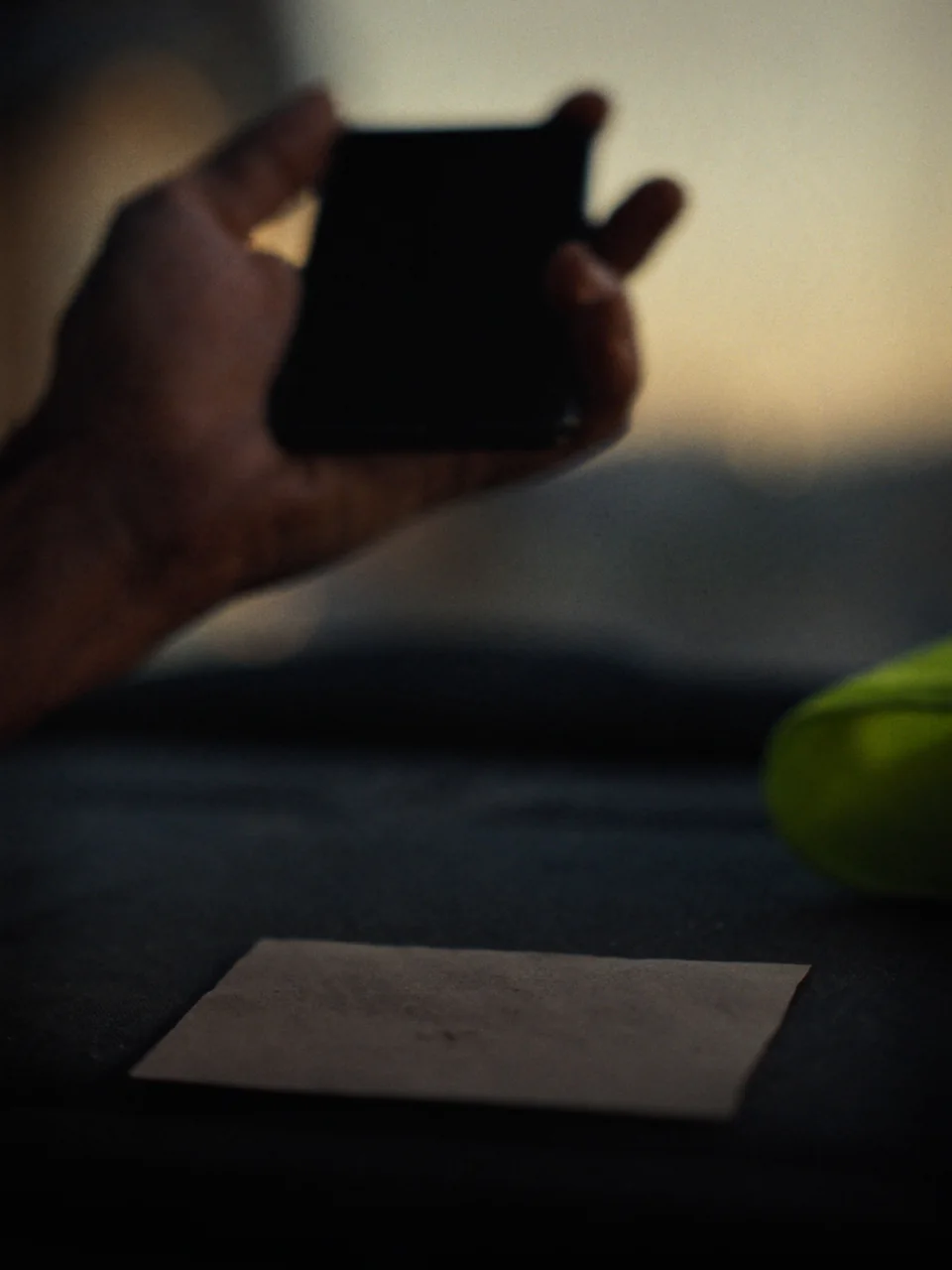 Sample photo: a hand holds a phone over a business card on a ute dashboard at sunrise