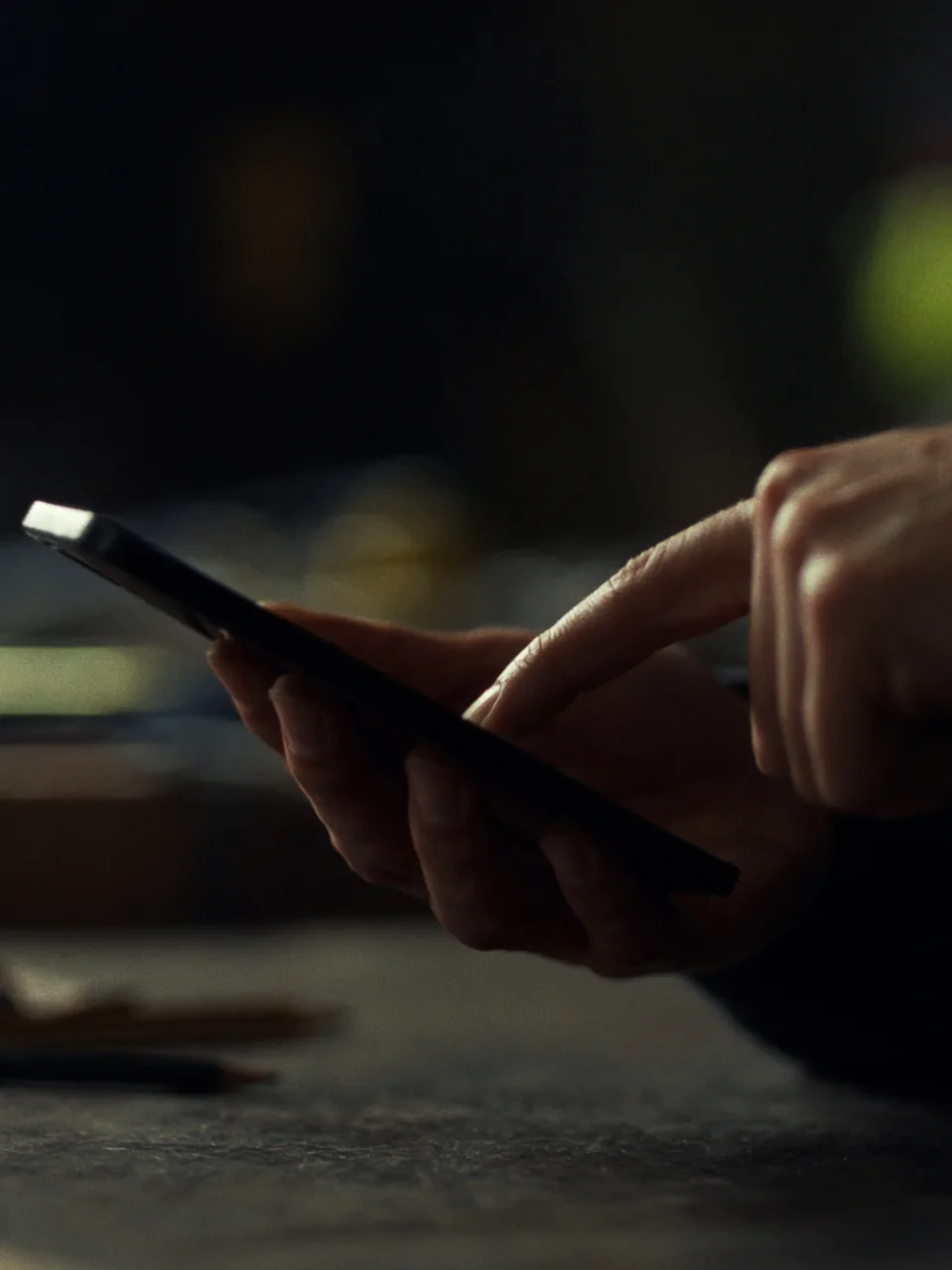 Sample photo: a tradesperson's hands tap a phone over a workbench
