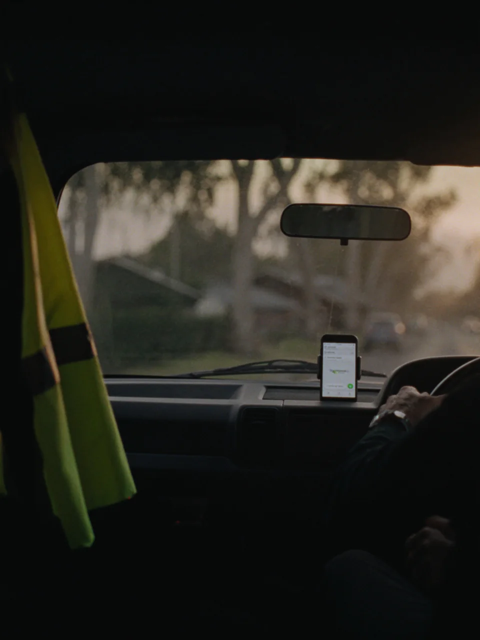 Sample photo: a phone in a dashboard mount inside a ute at sunrise, a hi-vis vest on the seat