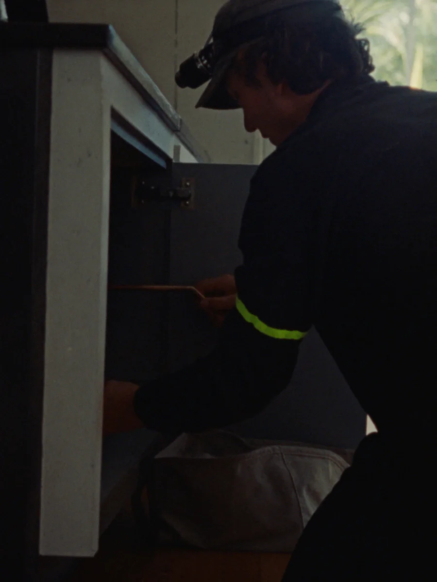 Sample photo: a plumber with a head torch works under a kitchen sink